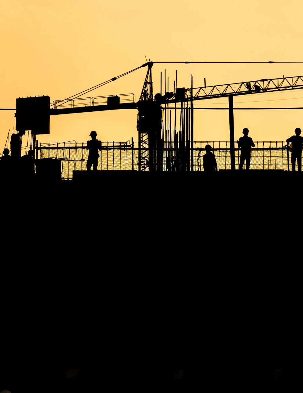 Dimly lit construction site with workers on roof