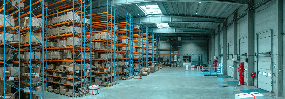 dimly lit warehouse with racks full of supplies on one side and bay doors on the other