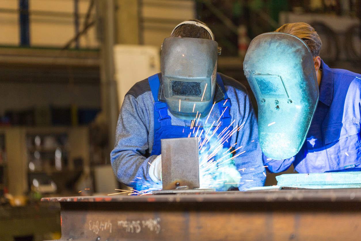 On-the-job training: junior welder studying technique during fabrication weld.